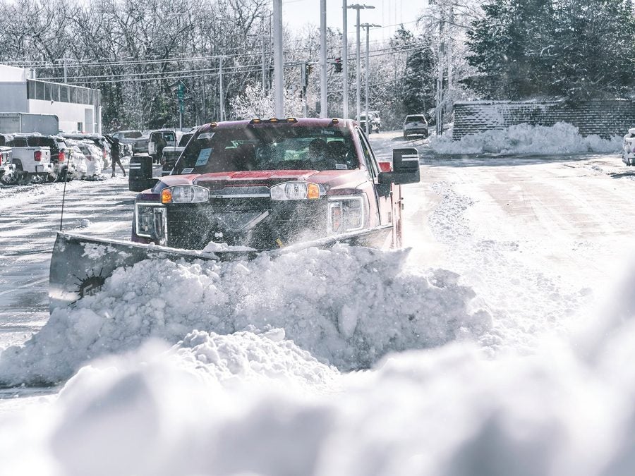 A Fisher plow truck pushing deep snow across the Marty's GMC lot in Kingston, MA
