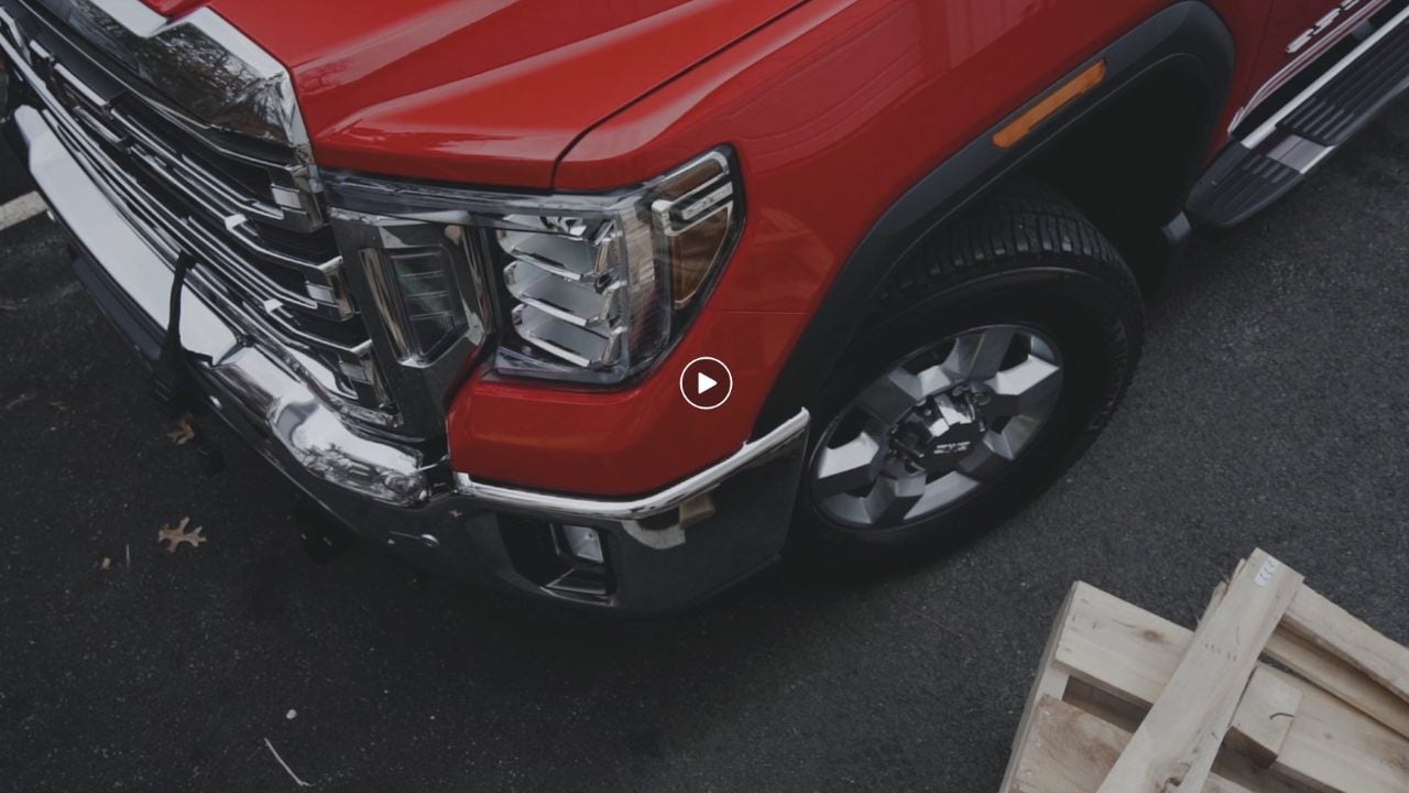 Still from the Marty's GMC Fisher plow video: a red GMC Sierra HD being fitted with a Fisher plow