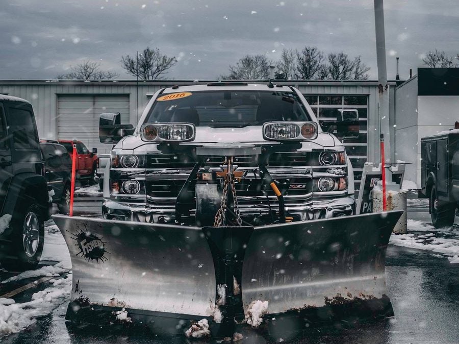 Fisher stainless steel v-plow on a Chevrolet Silverado 2500HD in falling snow at Marty's