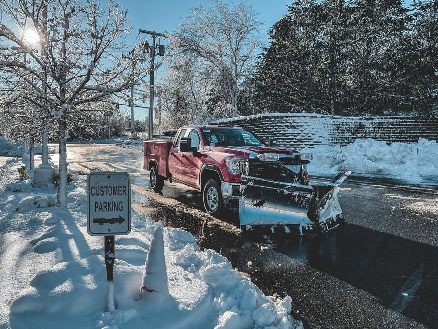 Fisher XV2 stainless v-plow on a red GMC Sierra 2500HD utility body truck after a snowstorm in Kingston, MA